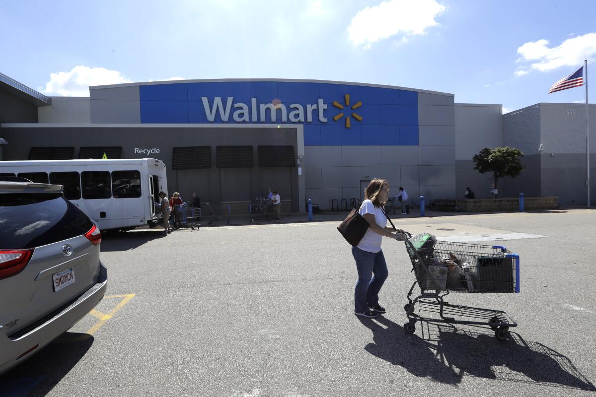A customer pushes a shopping cart outside a Walmart store, in Walpole, Mass. 