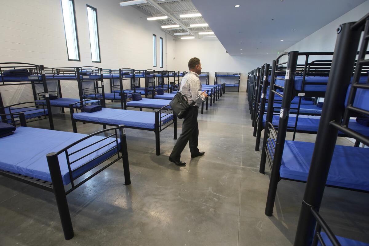 Preston Cochrane, executive director of Shelter the Homeless, walks through a room full of beds.