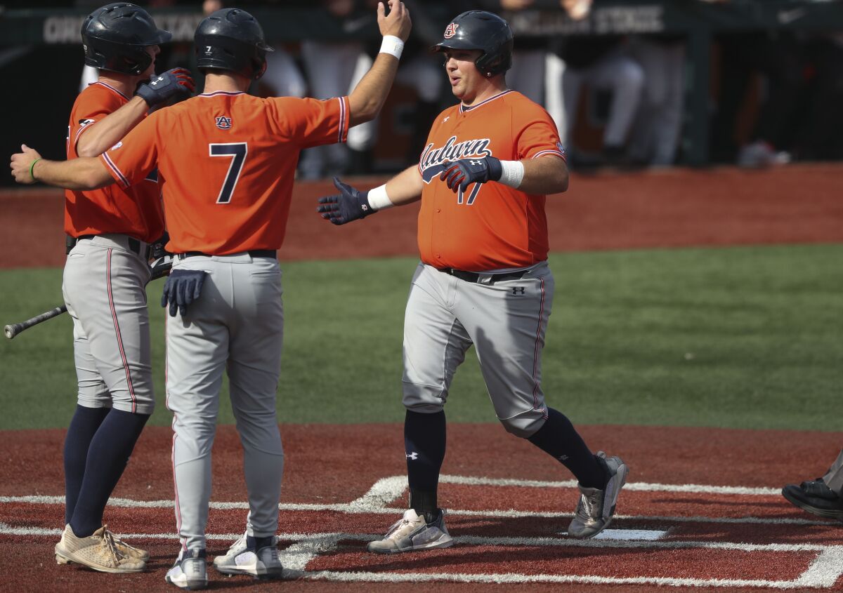 Auburn infielder Sonny DiChiara, right, celebrates with Cole Foster, center, and Bobby Peirce, left, after hitting a two-run home run during the third inning of an NCAA college baseball tournament super regional game against Oregon State on Monday, June 13, 2022, in Corvallis, Ore. (AP Photo/Amanda Loman)