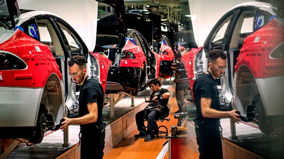 A worker assembling a Tesla vehicle is reflected in a computer screen at the automaker's factory in Fremont, Calif., in 2015.