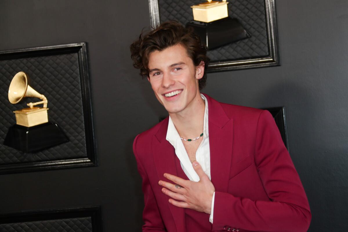 A man wearing a red suit with a white shirt places his hand over his hear