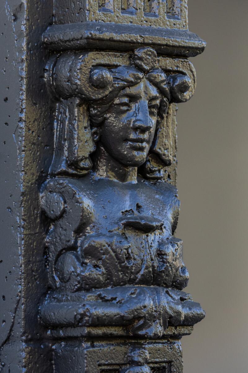 A decorative pillar with a carved person, their chest hidden by an acanthus leaf