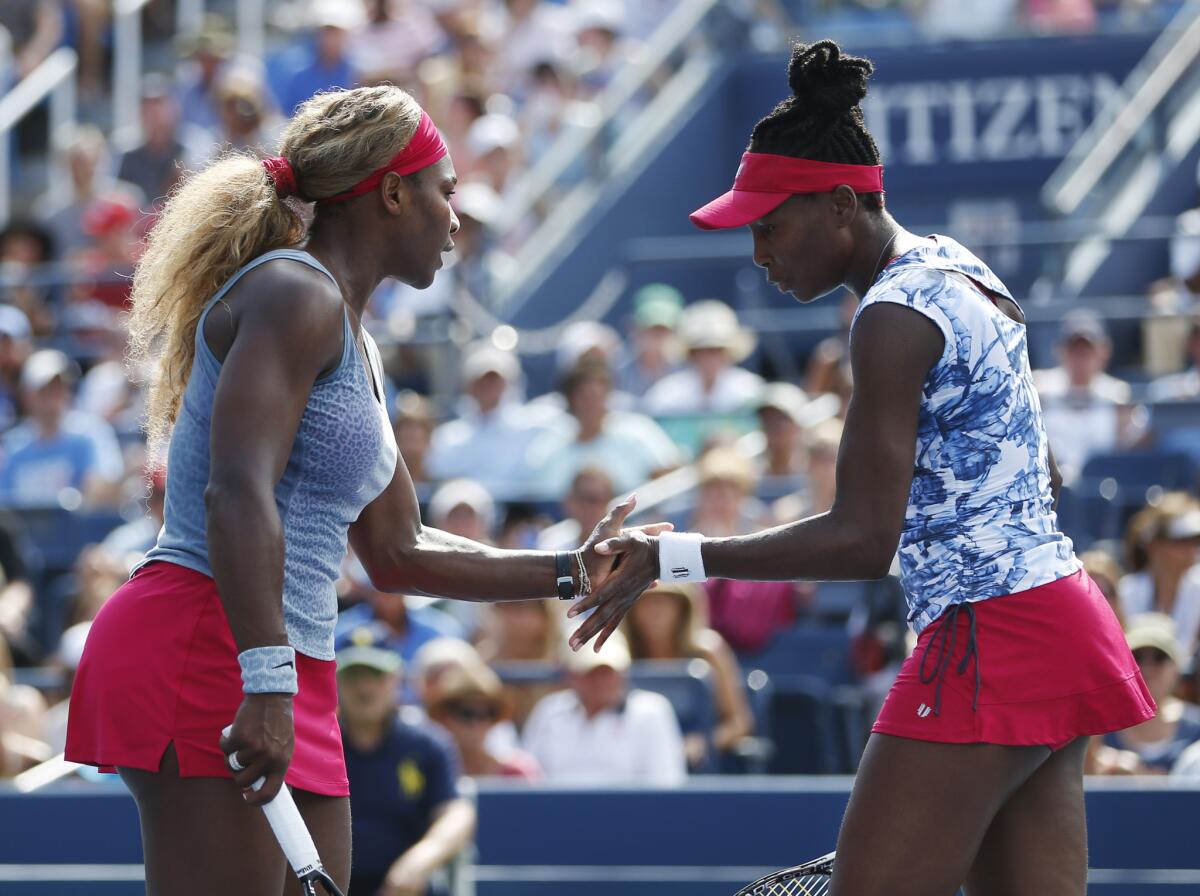 Serena, left, and Venus Williams slap hands between points during a doubles match at the 2014 U.S. Open in August.