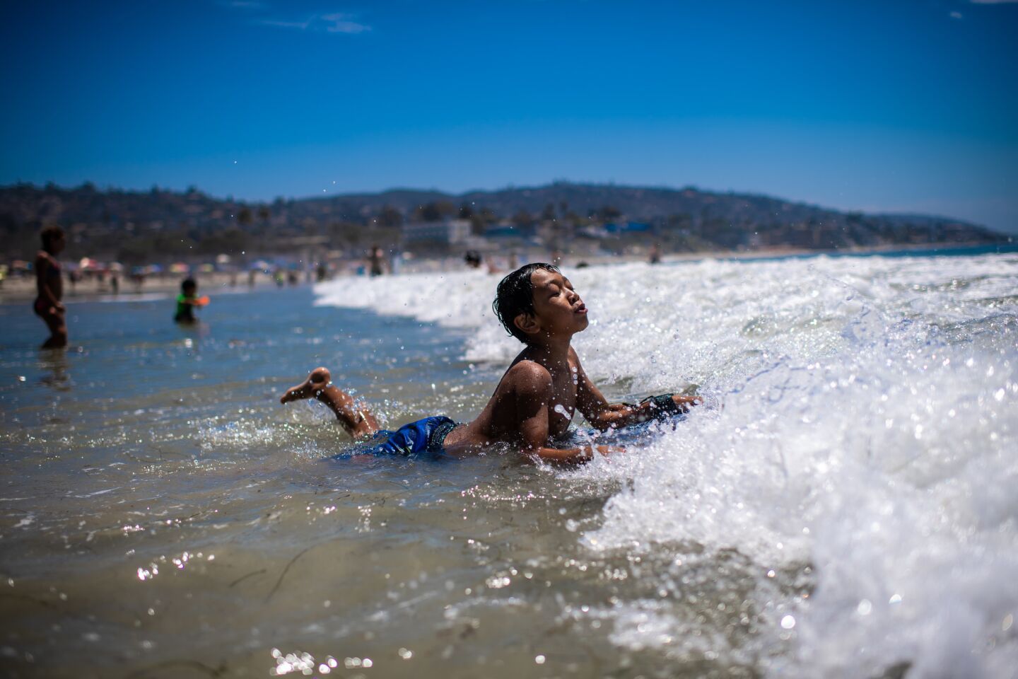 Daniel Navarro plays in the surf in Laguna Beach, where highs along the coast hit the 90-degree mark.