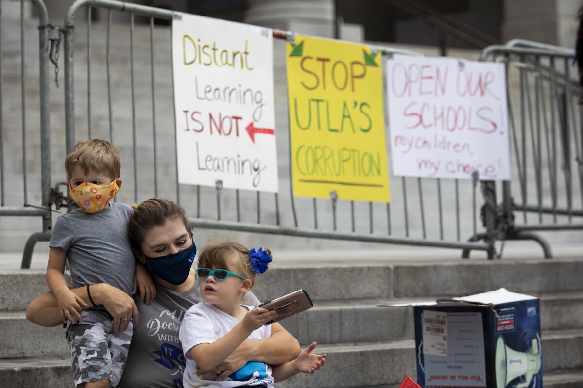 A woman holds two kids in front of protest signs