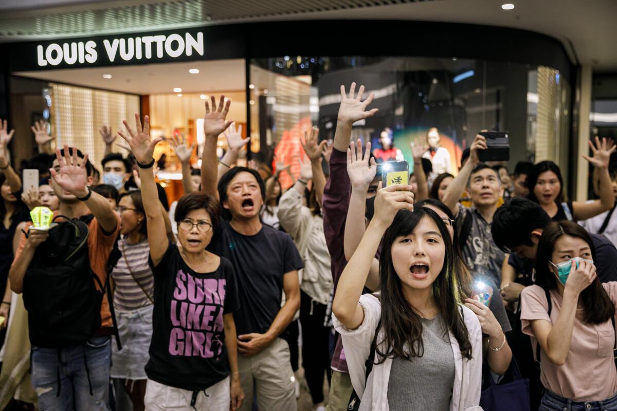 Protesters chant, "Five demands, not one less," at Times Square Shopping Center, in Hong Kong.