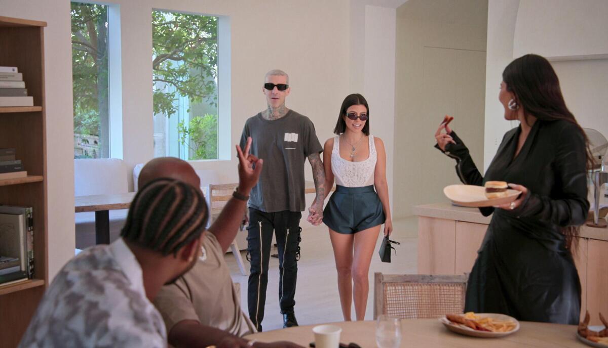 Travis Barker and and Kourtney Kardashian walk into a room during a family barbecue.