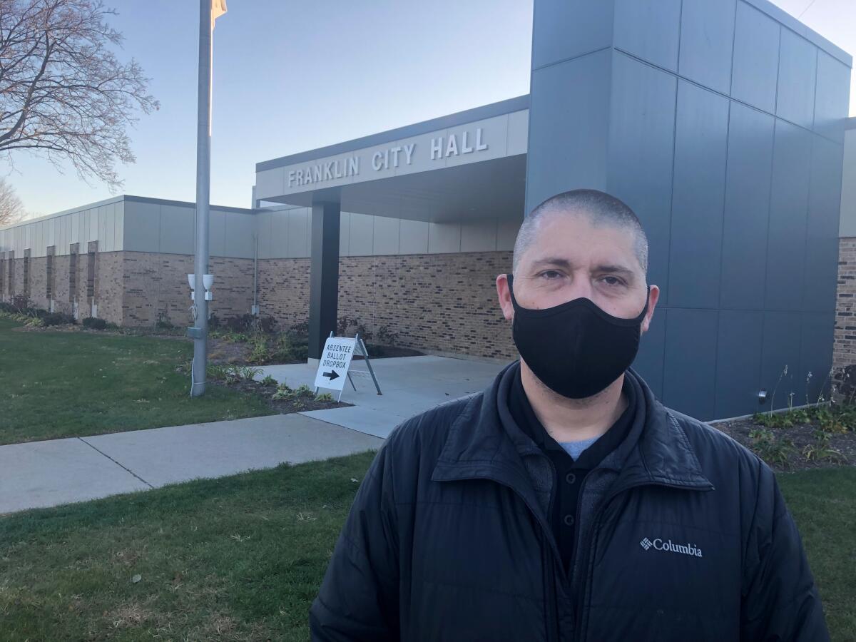 Joshua Liegler, in mask, stands in front of City Hall in the Milwaukee suburb of Franklin.
