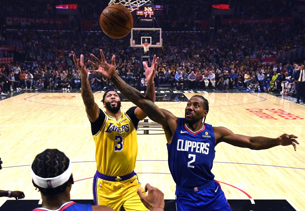 Lakers forward Anthony Davis, left, battling Clippers forward Kawhi Leonard for a rebound on Oct. 22, helped make their new teams instant title contenders.