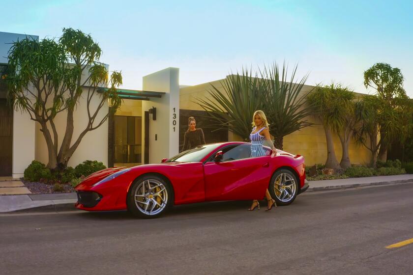 Two women getting into a bright red sports car outside an Orange County mansion