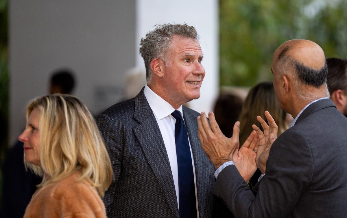 A smiling man with graying curly hair chats with another person at a museum gala.