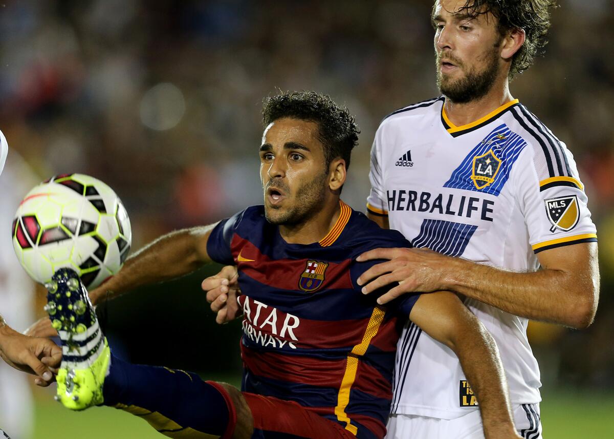 Galaxy defenseman Tommy Meyer, right, fights for control of the ball against FC Barcelona's Douglas in the second half of a match at the Rose Bowl on July 21.
