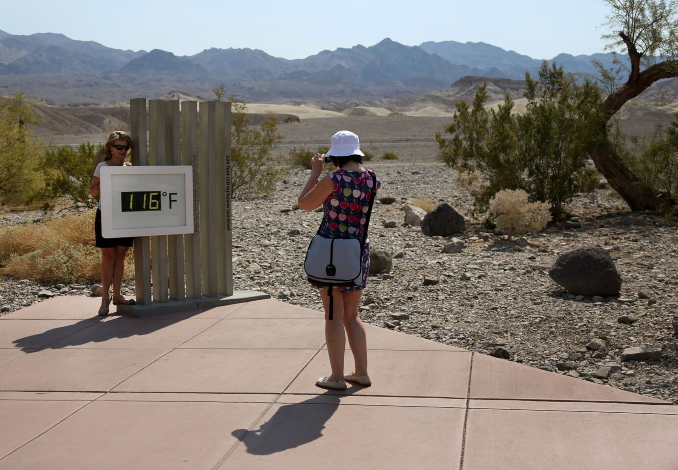 Conchi Almanza takes a photo of Mar Rodriguez in front of a digital thermometer at the Furnace Creek Visitor Center in Death Valley. The two tourists from Spain were likely to experience history Sunday with record temperatures forecast.