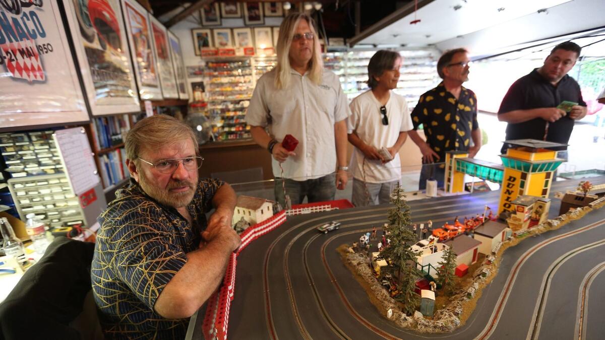 Michael Smalley, far left, watches fellow FarrOut Slot Car Club racers compete at a private track in Glendale.