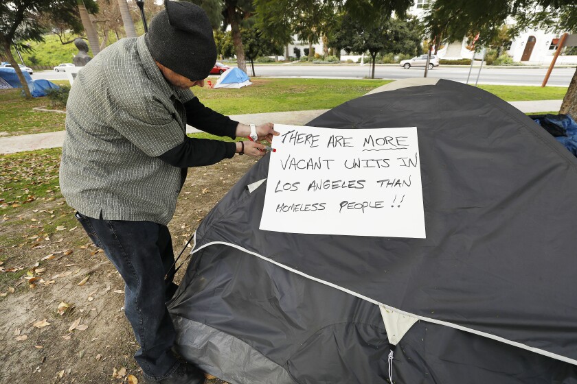 David Tyler, a homeless resident of Echo Park, posts a sign on his tent in Echo Park.