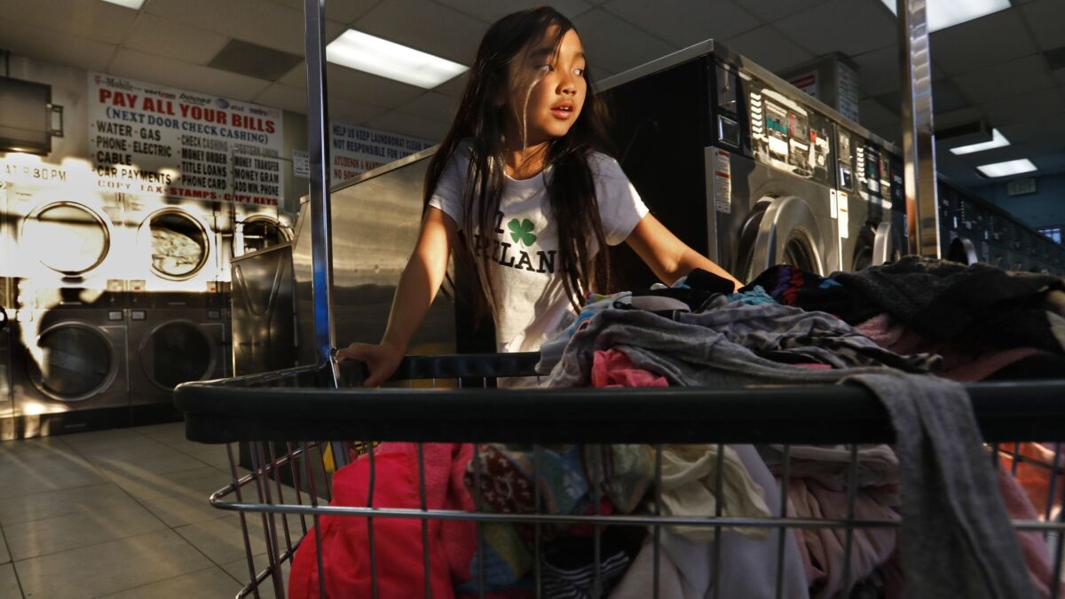Isabella Kap, 8, helps her grandmother at the laundromat in Long Beach, where members of the large Cambodian community often lend money to one another through informal groups rather than use banks.