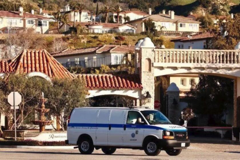 A coroner's van leaves the Renaissance gated community, where Los Angeles police investigated a triple homicide in February. Police arrested a man and woman this week in Maryland and another man in North Carolina. (Al Seib / Los Angeles Times)