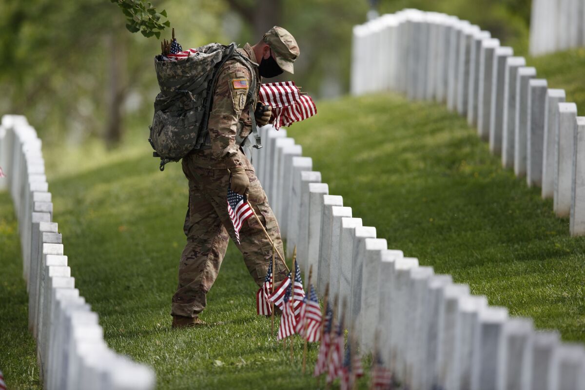 A member of the 3rd U.S. Infantry Regiment places flags in front of each headstone at Arlington National Cemetery.