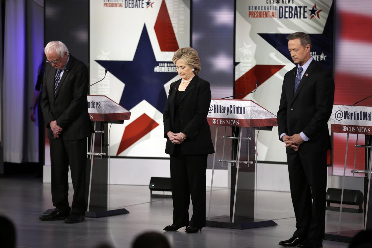 Democratic presidential candidates Bernie Sanders, left, Hillary Rodham Clinton and Martin O'Malley take a moment of silence for those killed in the Paris attacks before the second Democratic presidential debate, in Des Moines, Iowa.