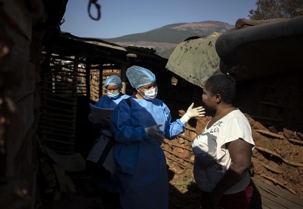 A health worker in blue attire, left, speaks to a woman.