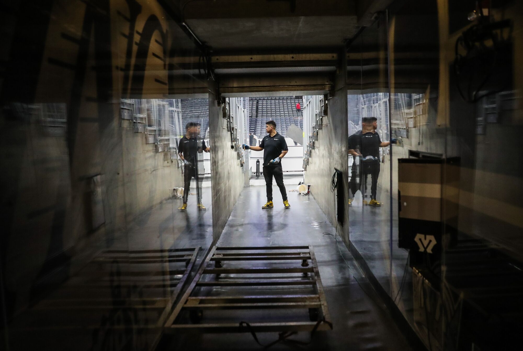 Un employé de Crypto.com Arena sécurise les panneaux de plexiglas sur un coin salon adjacent au tunnel de l'équipe.