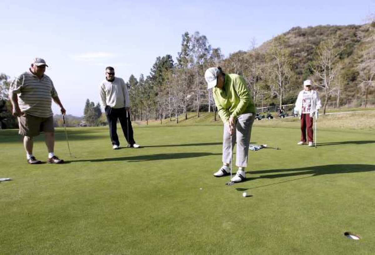 Sandra Pessaro puts one as, from left, Ed Pape, Joaquin Herbozo and Jeannie Smith look on at the 10th Annual Guys and Dolls Golf Tournament at DeBell Golf Club in Burbank.