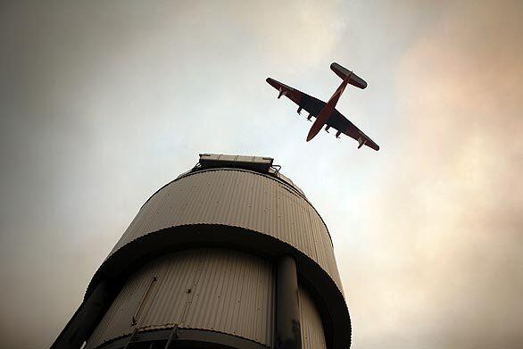 A Martin Mars Super Scooper flies over one of the telescopes atop Mt. Wilson, moments before dropping 7,200 gallons of water to keep flames away from the Mt. Wilson Observatory and radio towers Tuesday.