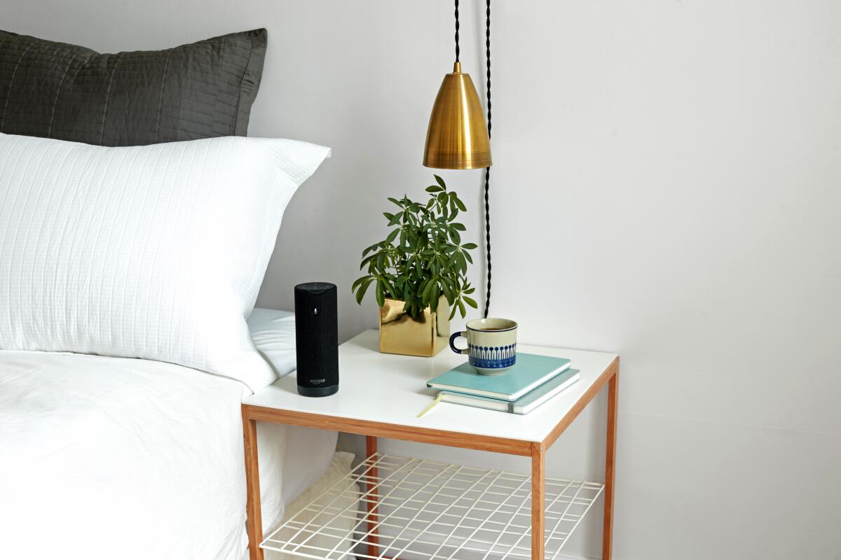 An Amazon Tap sits on a bedside table.