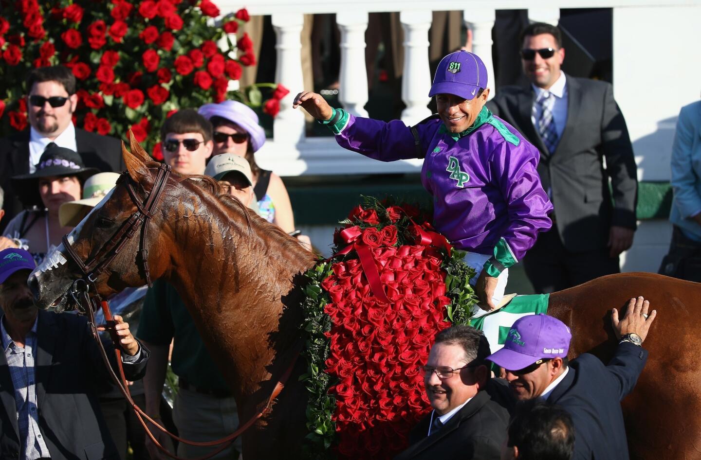 Jockey Victor Espinoza and California Chrome bask in roses in the Winner's Circle at Churchill Downs after claiming victory in the 140th Kentucky Derby on Saturday.