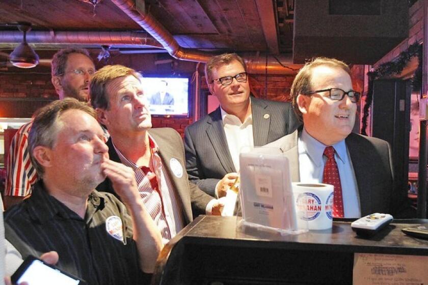 Costa Mesa City Council candidates Gary Monahan, far left, and Steve Mensinger, second from right, watch early returns in the council race on Tuesday. Mayor Pro Tem Jim Righeimer, at right, also watches.