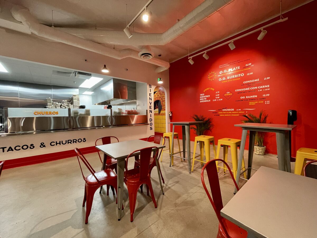 The menu on a bright red wall welcomes diners inside Papi Tacos & Churros on South Main Street in Santa Ana.