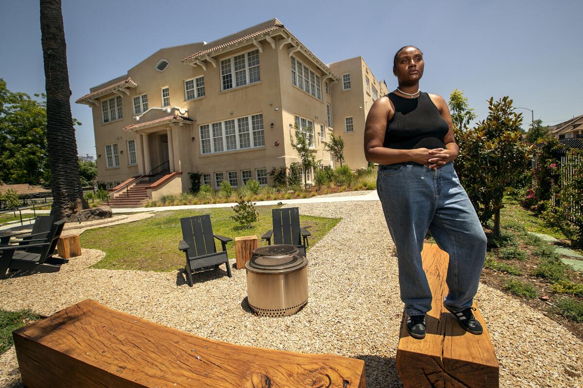 Zahria Eaves stands on a long piece of wood in a yard in front of a building.