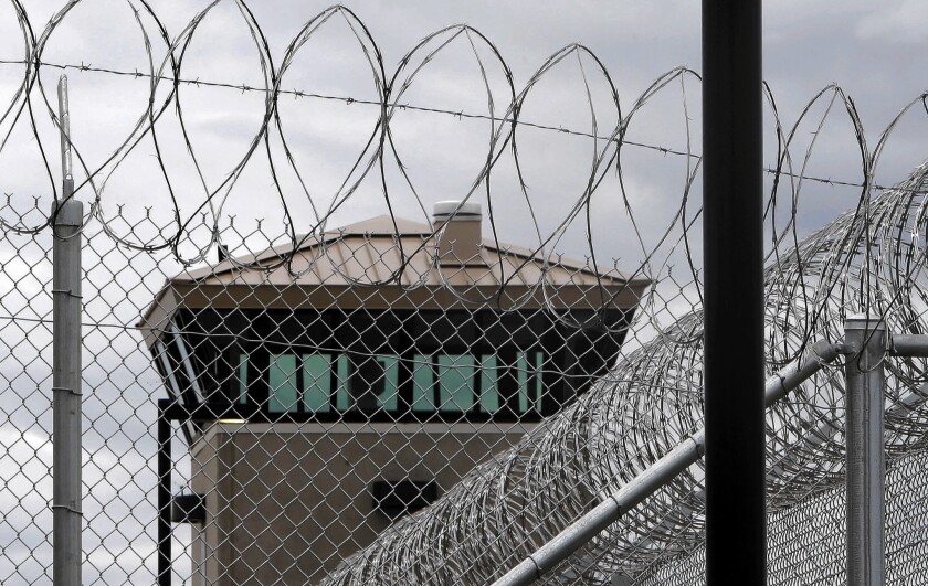Barbed wire tops fences in front of a watchtower at a prison