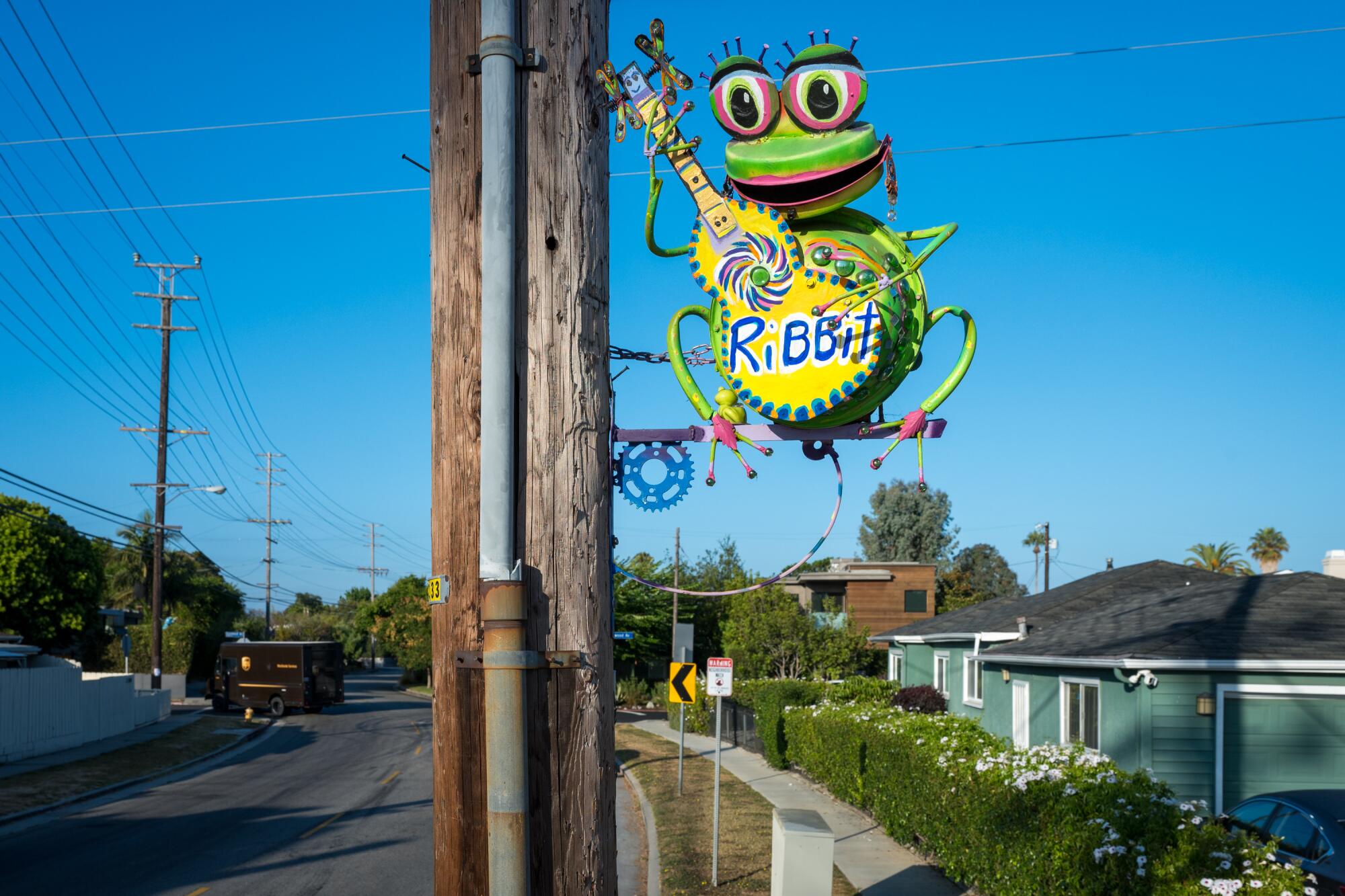 A frog-like sculpture on a pole.