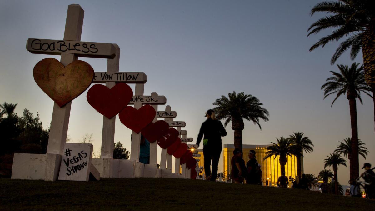 With the Mandalay Bay in the distance, a woman walks past the wooden crosses bearing the names of those killed in the Oct. 1, 2017, mass shooting in Las Vegas.