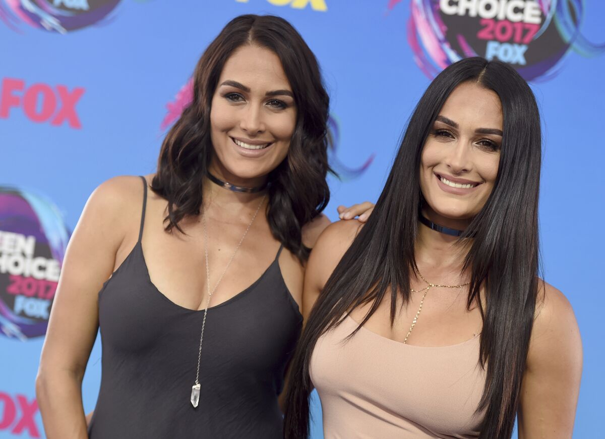 A woman with short dark hair in a dress posing with a woman with long dark hair who strongly resembles her