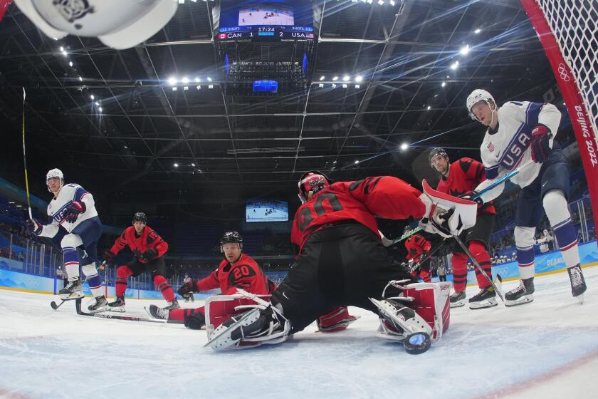 American Brendan Brisson, left, scores a goal against Canadian goalkeeper Eddie Pasquale as others look on