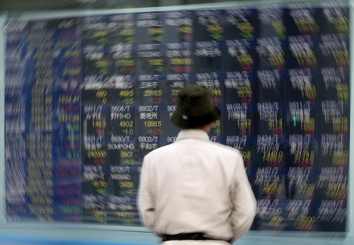 A pedestrian pauses in front of an electronic board at the Tokyo Stock Exchange on Tuesday.