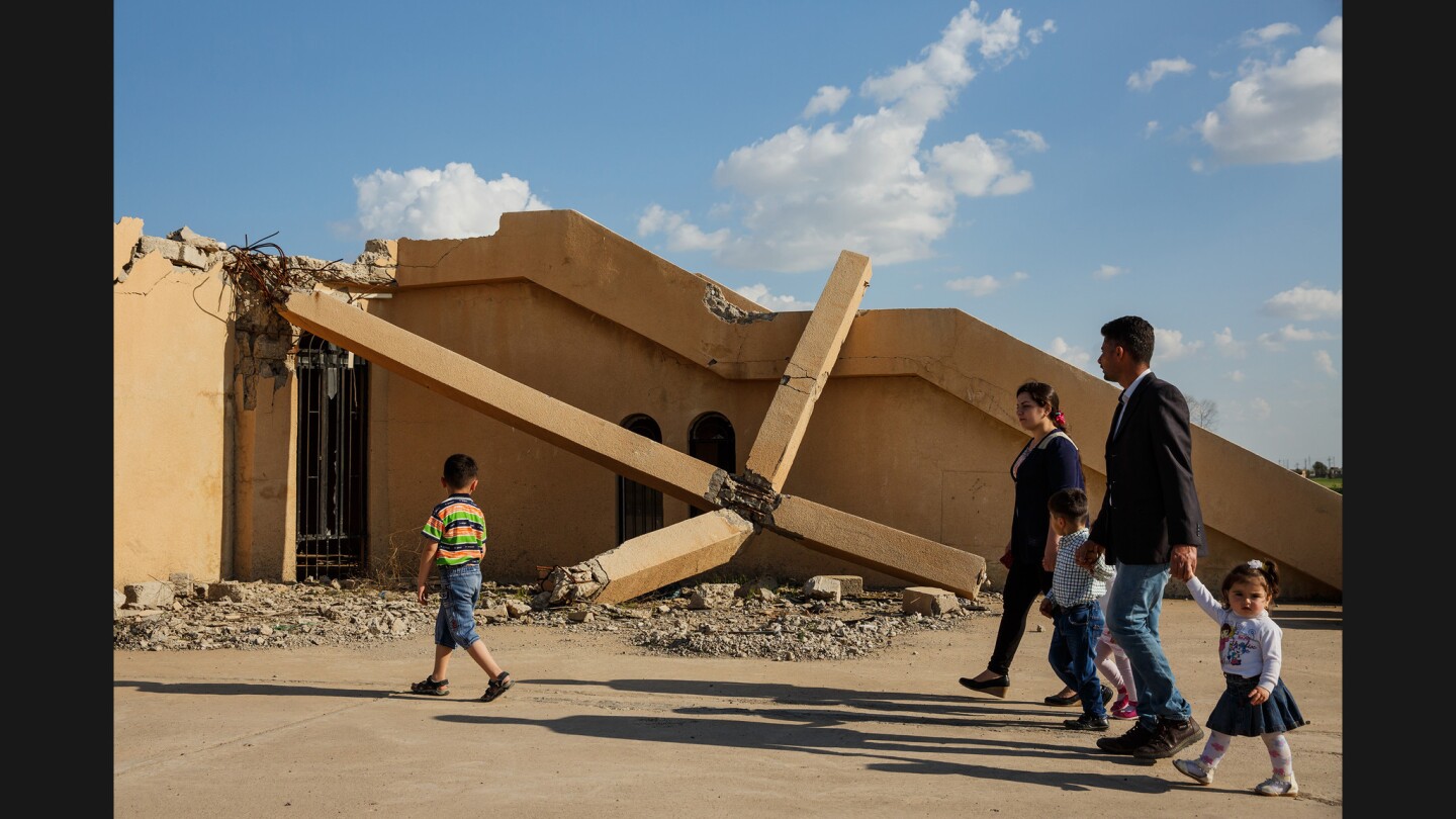 Razwan Paul Sony, wife Lina Hannah and their children walk past a destroyed cross on their way to visit the grave of Sony's mother to observe Easter in Qaraqosh, Iraq.