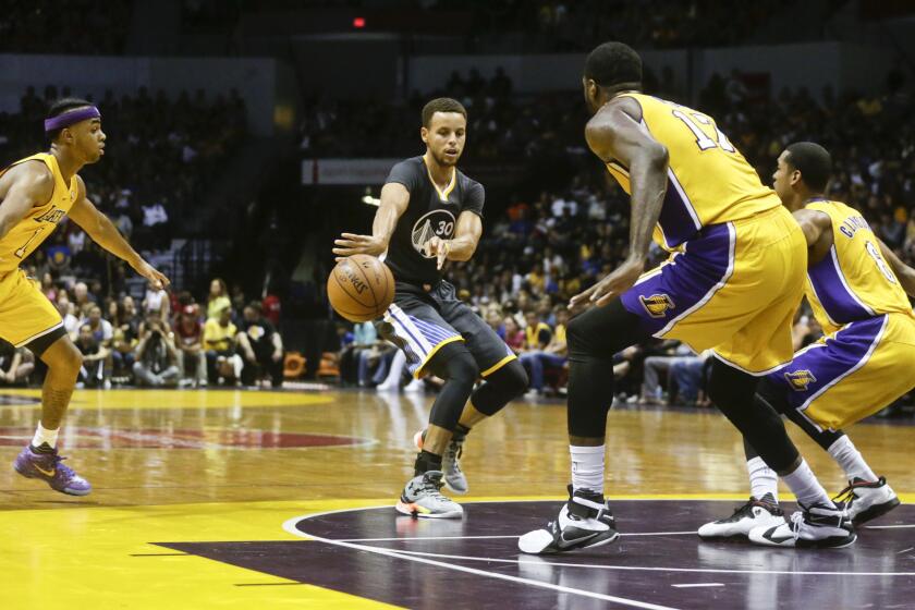 Golden State Warriors guard Stephen Curry splits the Lakers' defense with a fast-break pass during the first half of a preseason game on Oct. 17.