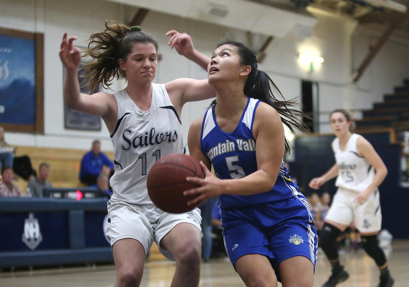 Fountain Valley High's Kat Luu drives past Newport Harbor's Chloe Swanson for a layup during a Wave League girls' basketball game on the road Thursday.