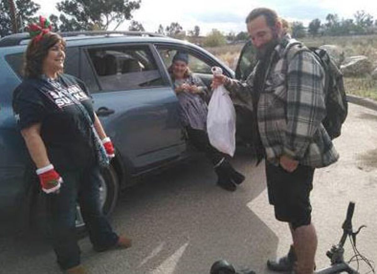 A homeless man, right, accepts essentials inside a goodie bag provided through a past Homeless Care Kit Drive.