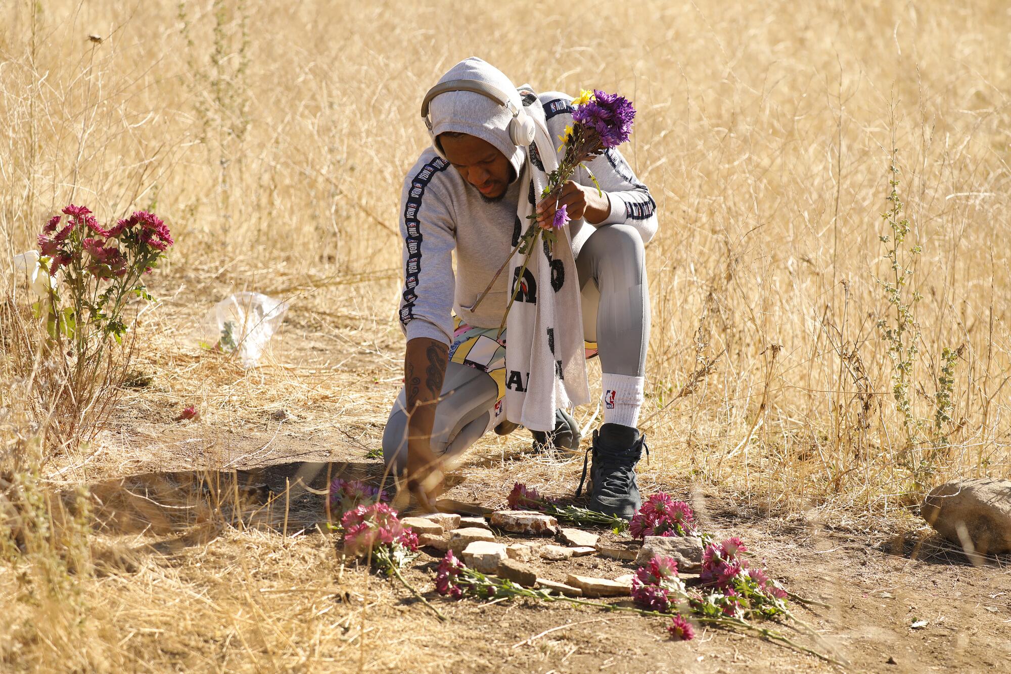 Dontate Matthews, 30, of Calabasas places flowers on rocks arranged to form the number 8 in Calabasas.