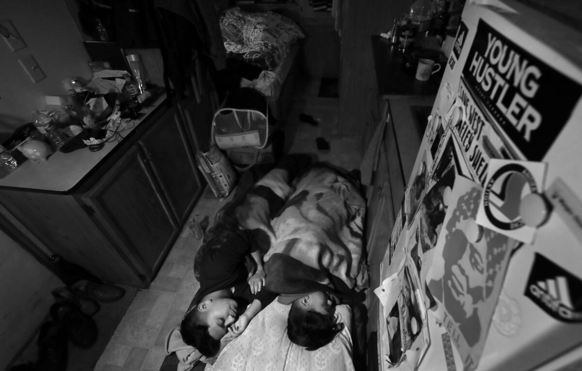 Ismael Chamu, left, and his brother Edward, sleep on the floor of their mobile home while their sisters share the sole bed. Because living in residential trailers is outlawed in Hayward, the family will be evicted soon and have to find new housing.