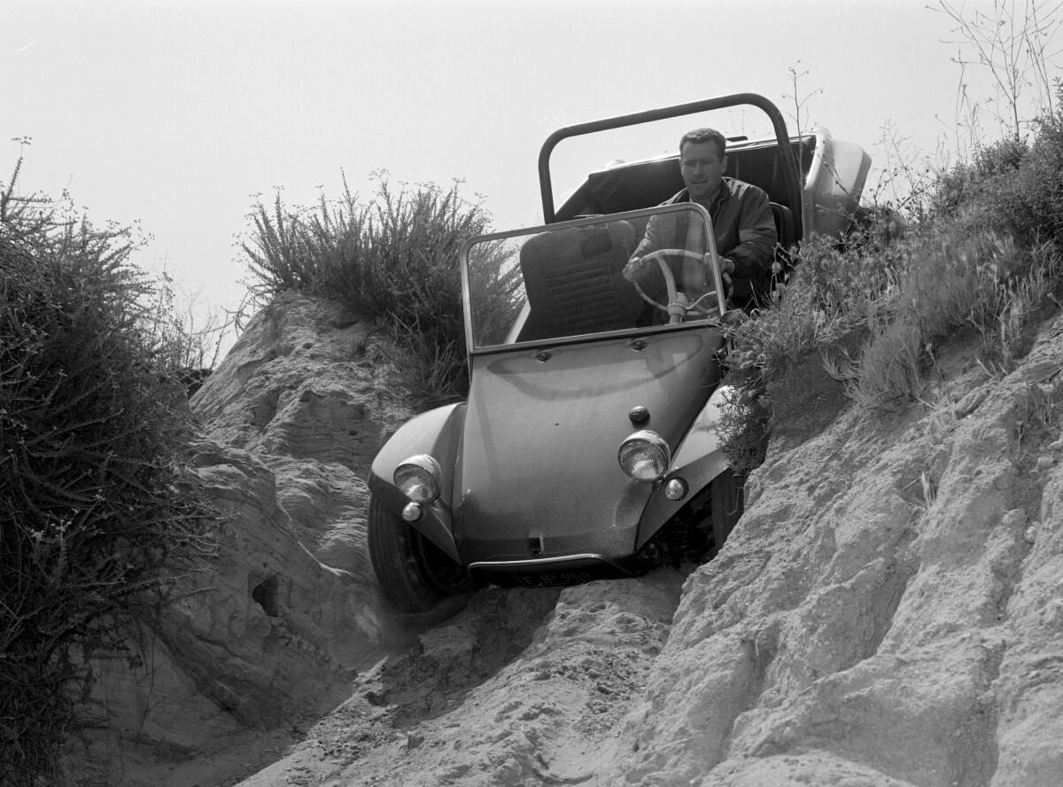 Bruce Meyers in his Manx dune buggy going down a sand dune.