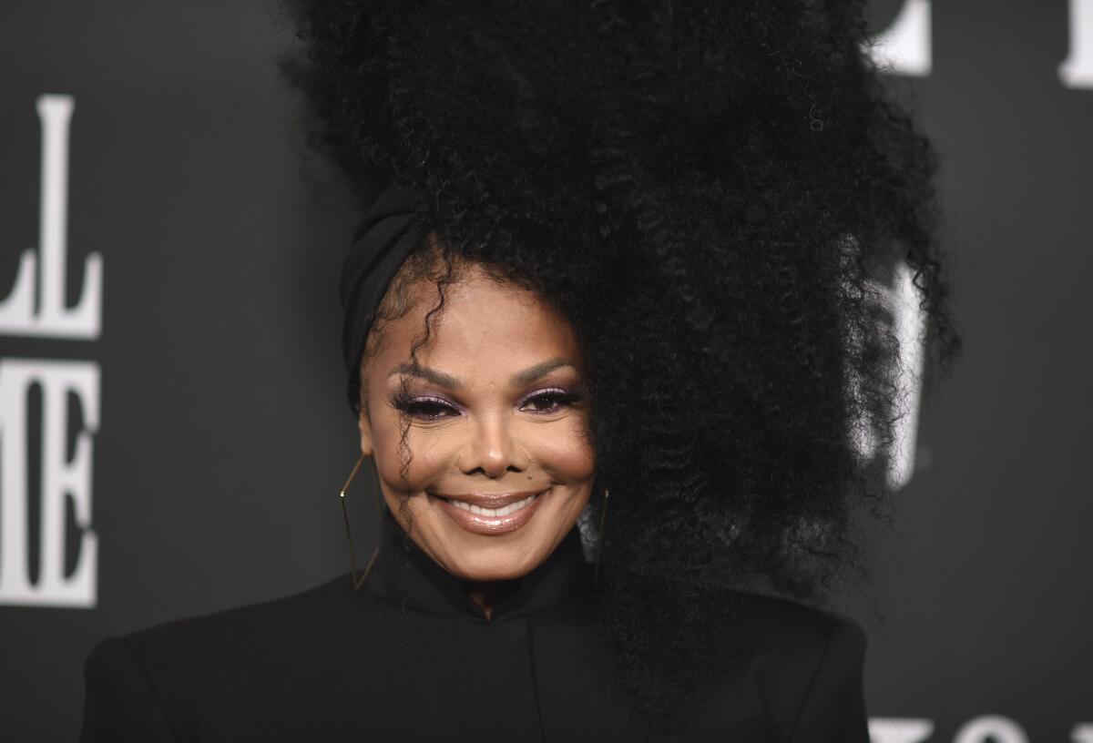 Janet Jackson smiles in a black turtleneck.
