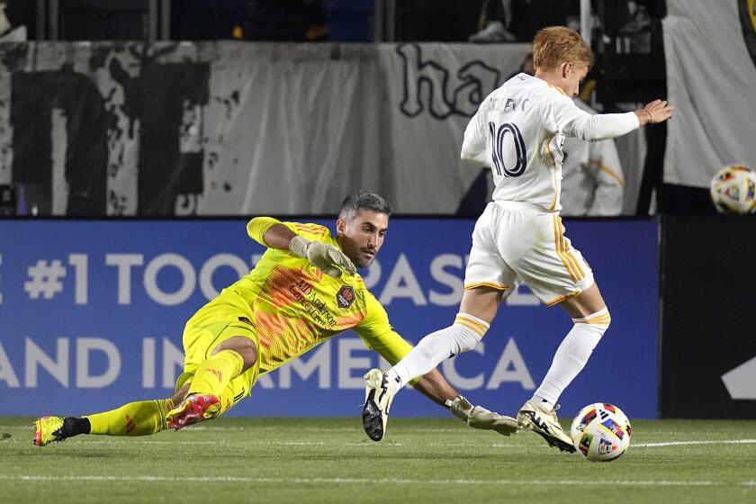 Houston Dynamo goalkeeper Andrew Tarbell, left, tries to stop LA Galaxy midfielder Riqui Puig during the first half of a Major League Soccer match Saturday, May 25, 2024, in Carson, Calif. (AP Photo/Mark J. Terrill)