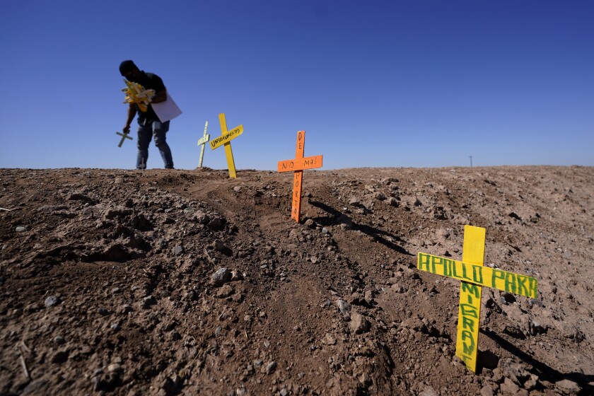 Hugo Castro leaves crosses at the scene of a deadly crash in Holtville, Calif., Tuesday, March 2, 2021. Authorities say a semitruck crashed into an SUV, killing multiple people. (AP Photo/Gregory Bull)