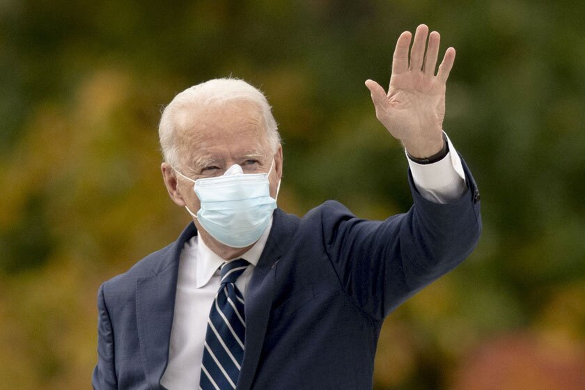 President Biden waving while wearing a blue face mask