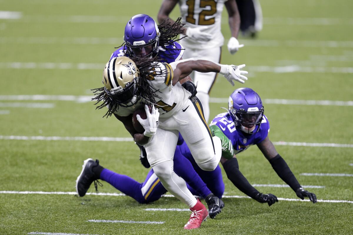 Saints running back Alvin Kamara carries the ball in front of Vikings safety Anthony Harris and cornerback Jeff Gladney.